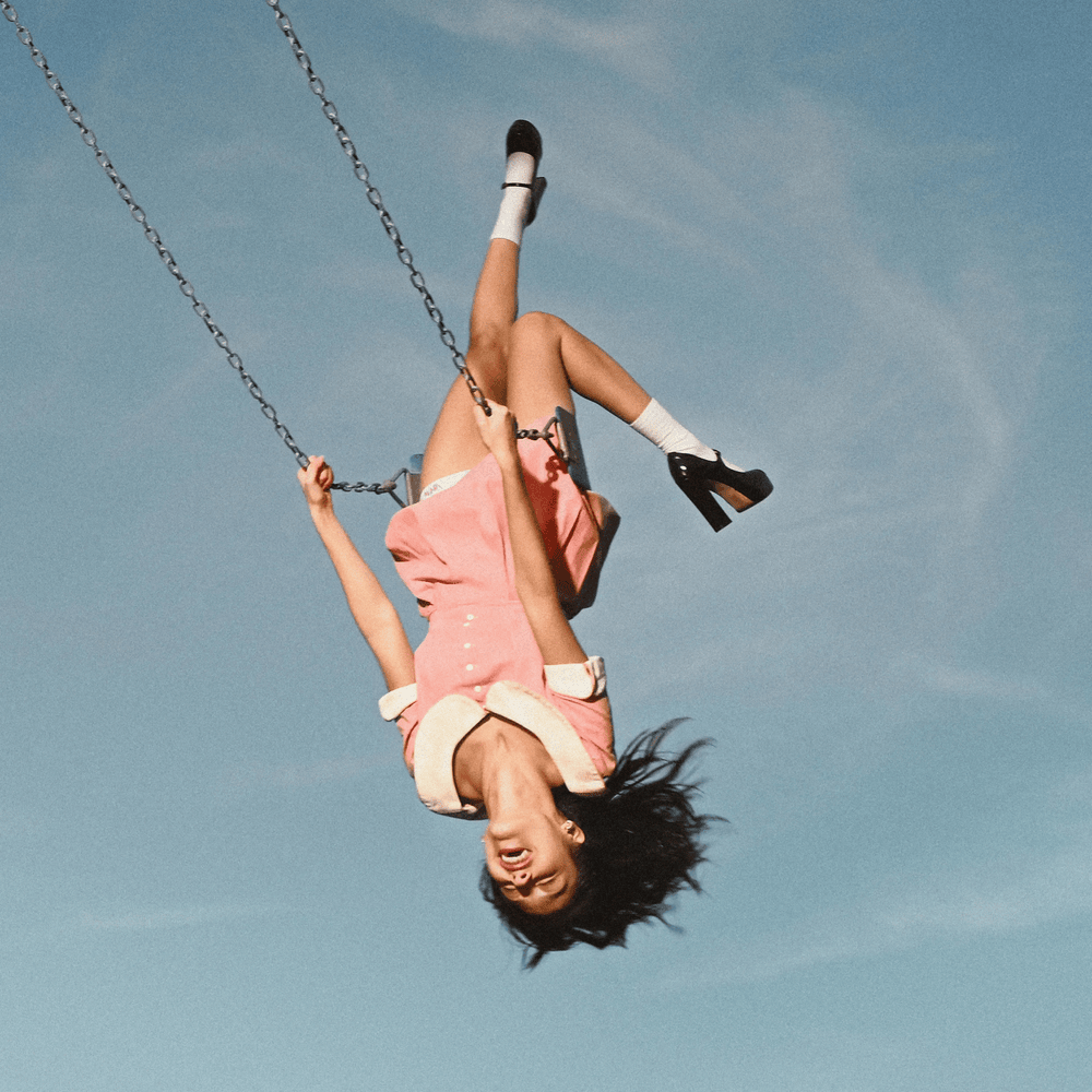 Chad Moore, woman upside-down on a swing against a blue sky